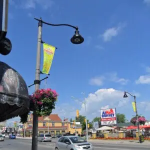 K829 Aurora Sr. - Fluted Tapered - 2 - Clifton Hills A K829 Aurora Sr. fixture accompanied by a pipe style arm, banner arms all on a Fluted Tapered pole, and flowerpot holders. This project is in Clifton Hills, located in Niagara Falls, Ontario.