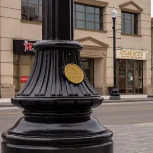 A KSB16 Florentine Sr. decorative split base accompanied by a custom 'Oakville' emblem on a fluted pole. This project is on one of the busy streets of Oakville, Ontario.