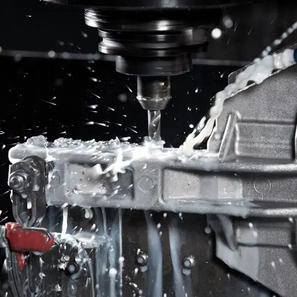 An employee at King Cast using tools from our manual machine shop to drill a hole into a piece of metal.
