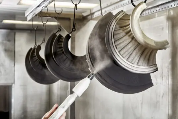 An employee at King Cast applying a powder coating to multiple King split bases.