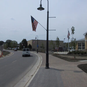 A K823 Falconridge Sr. fixture accompanied by banner arms, a Bishop Crook style arm, and a flag mount on top of a Classic pole.