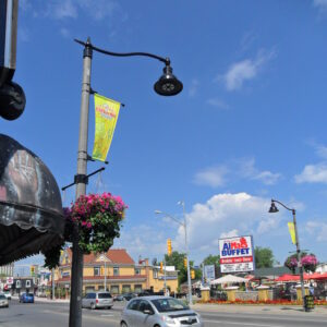 A K829 Aurora Sr. fixture accompanied by a pipe style arm, banner arms all on a Fluted Tapered pole, and flowerpot holders. This project is in Clifton Hills, located in Niagara Falls, Ontario.