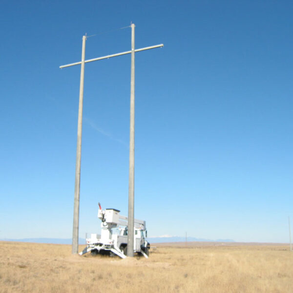 A spun concrete utility pole with an 'H Structure' application. This project is in a flat, farmland area with mountains in the background.